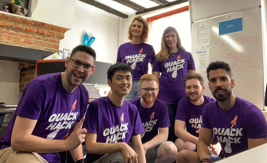 Group photo of Cyber-Duck employees wearing purple Quack Hack t-shirts for a hackathon