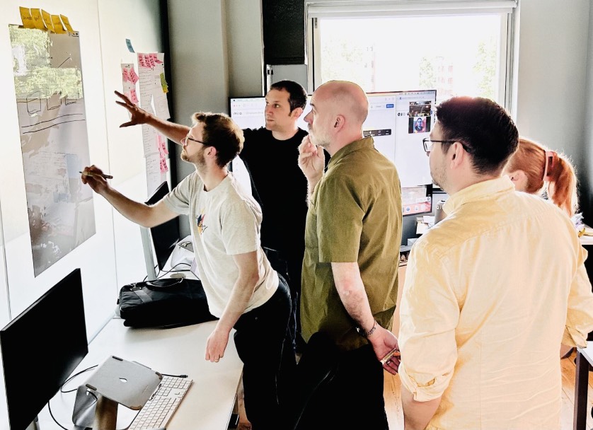 Four members of the team at Cyber-Duck all looking at a hand drawn wireframe on a wall