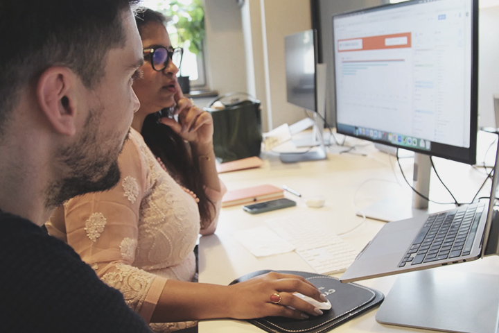 Side-on view of two members of the SEO team looking at a monitor in the office