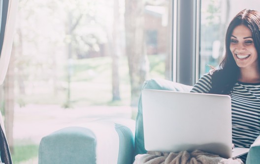 A young woman sitting in her living room whilst on her laptop