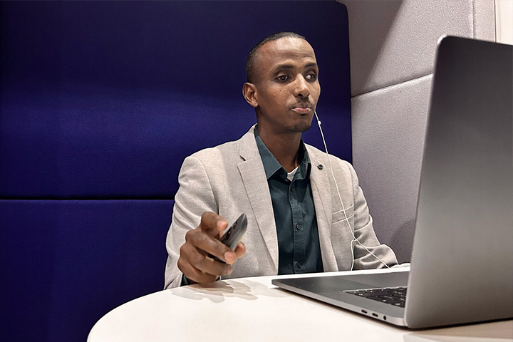 Man sitting at laptop with headphones on whilst running a webinar