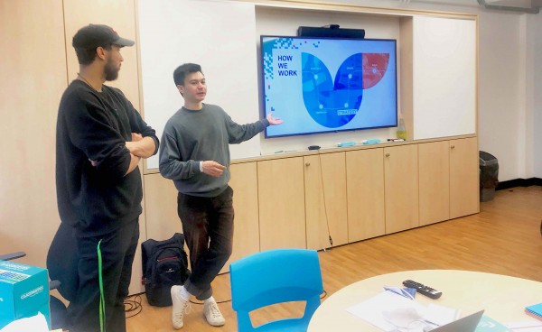 Mark and Chris presenting at the front of the class at BIMA Digital Day. Chris is pointing to a screen with the words How we work above the Cyber-Duck logo.