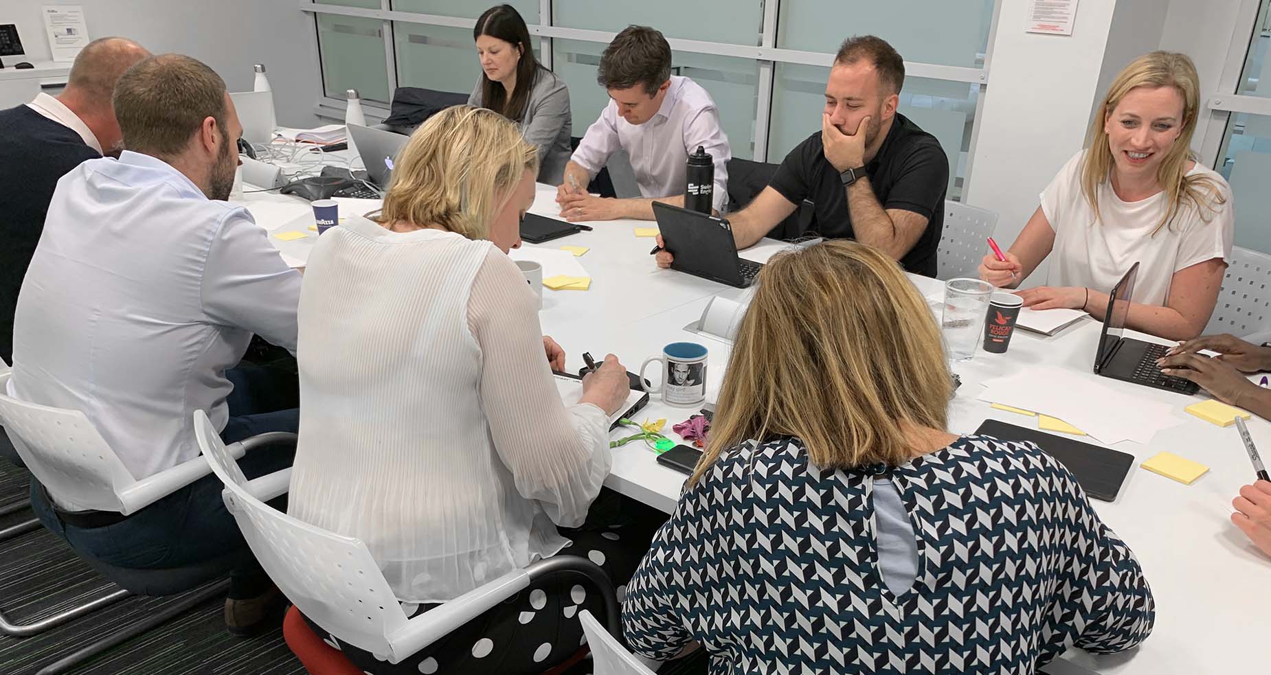 Photo of the Sport England team sitting at a long conference table contributing to a workshop