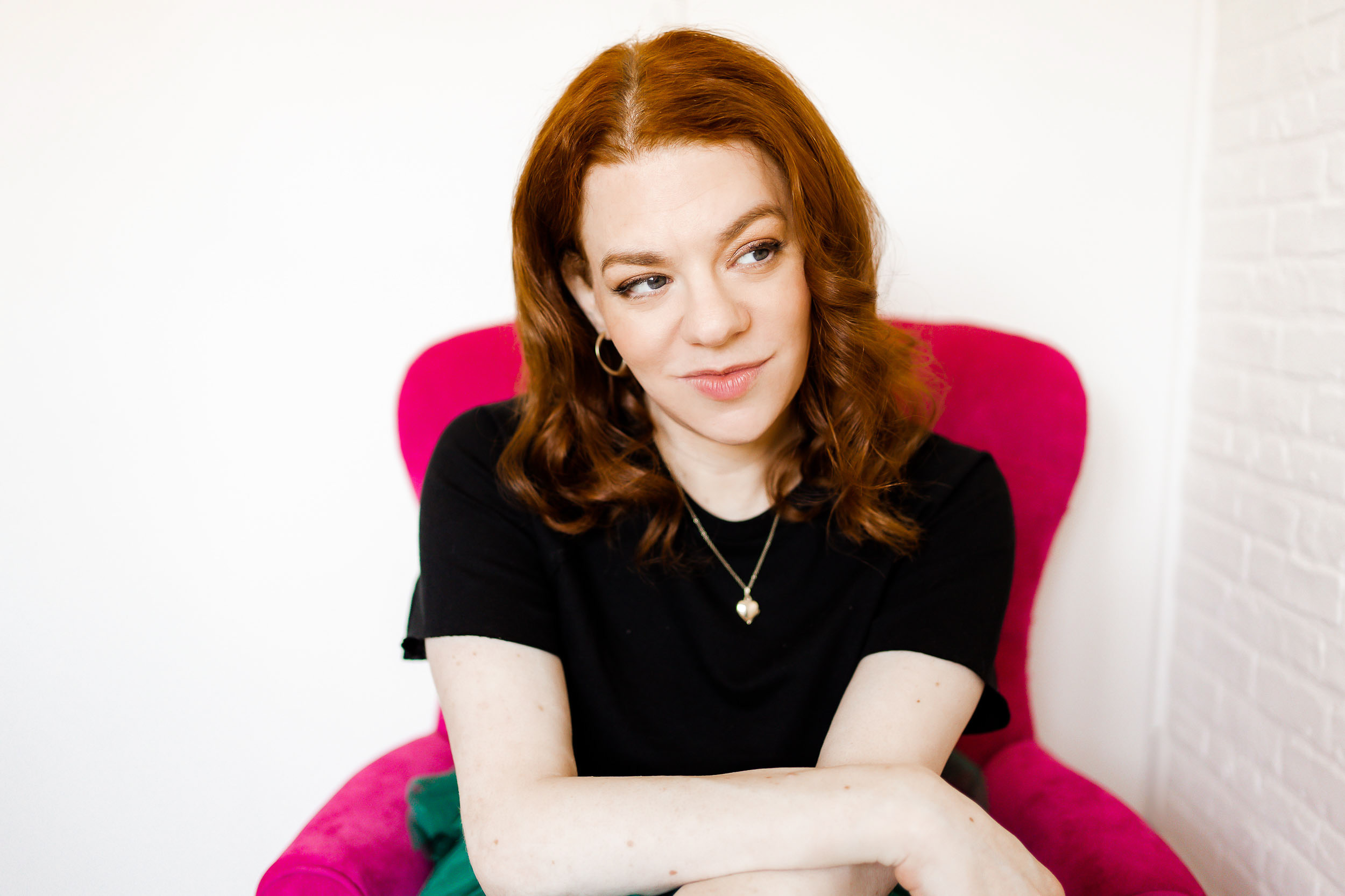 Headshot of Sara Gibbs on pink chair