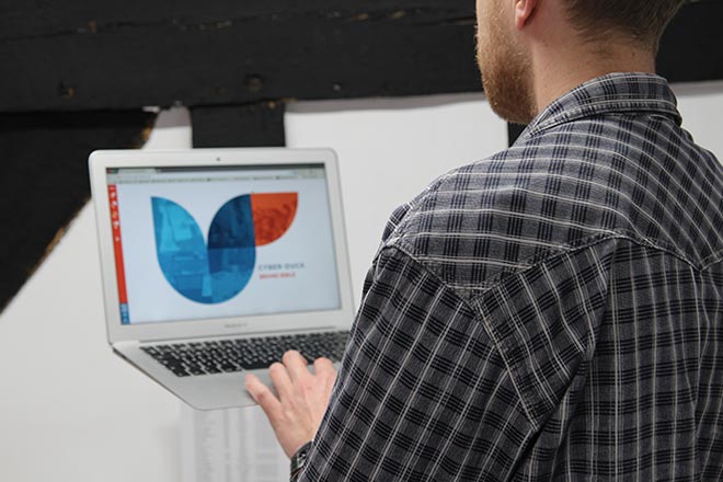 Jordan holding a MacBook with Cyber-Duck's Brand Bible