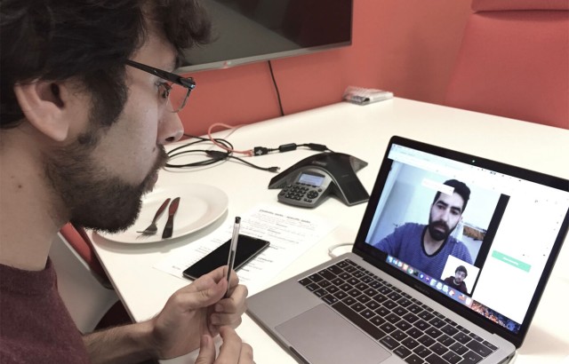 A man sitting in front of a computer zoom calling a team mate 