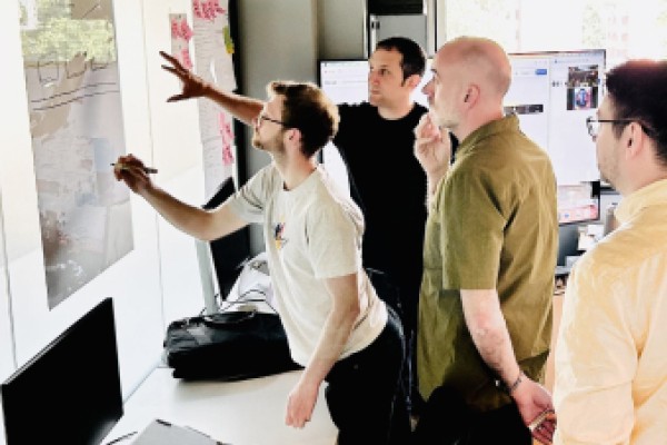 Four members of the team at Cyber-Duck all looking at a hand drawn wireframe on a wall