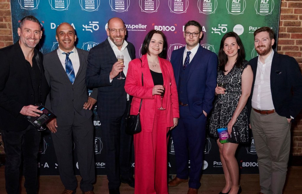 Staff members formally dressed standing together smiling for the camera at the BD100 awards