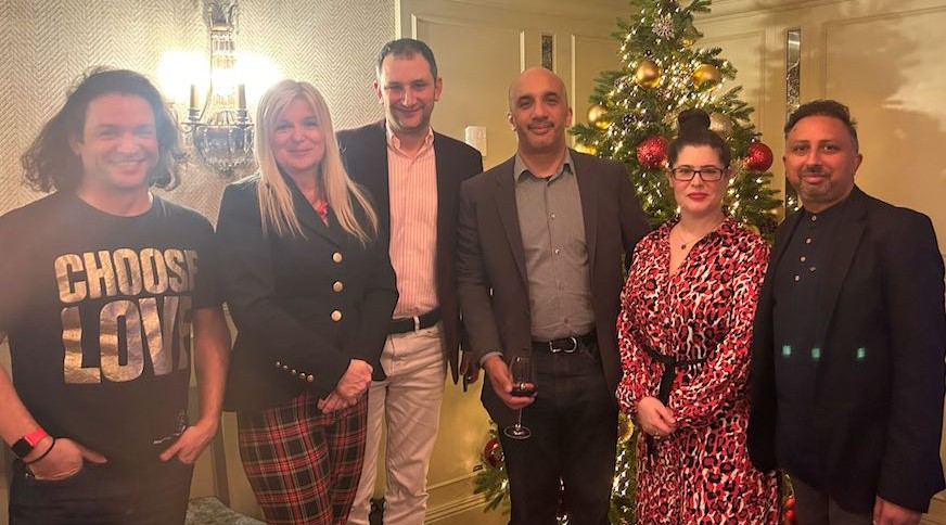 A photo of CEO Danny standing in a room with colleagues and clients for a photo in front of a Christmas tree