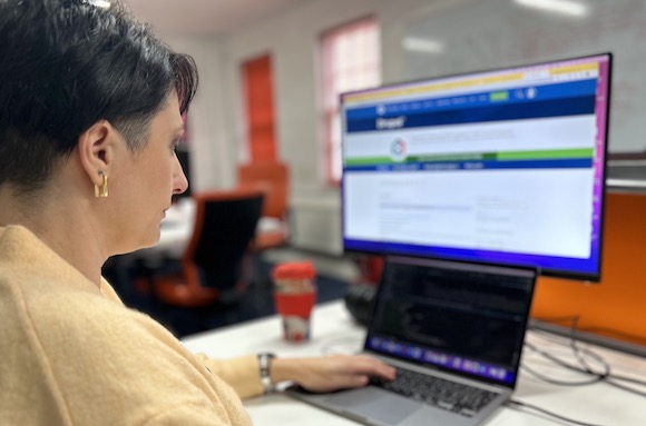 Photo of developer Alina coding at her desk with a laptop and monitor