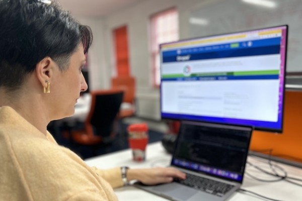 Photo of developer Alina coding at her desk with a laptop and monitor