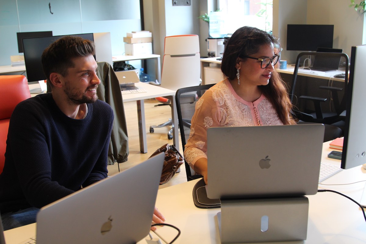 Two members of the digital optimisation team with laptops in front of them looking at a monitor at their desk