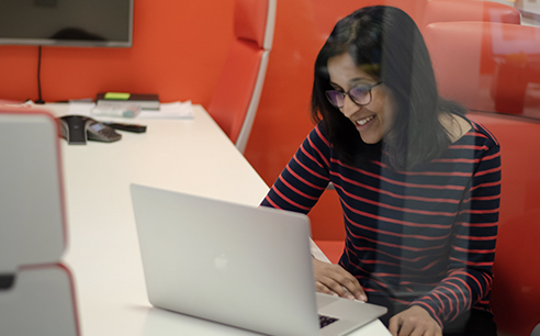 Photo of a Cyber-Duck employee at a conference table, smiling and looking at her laptop