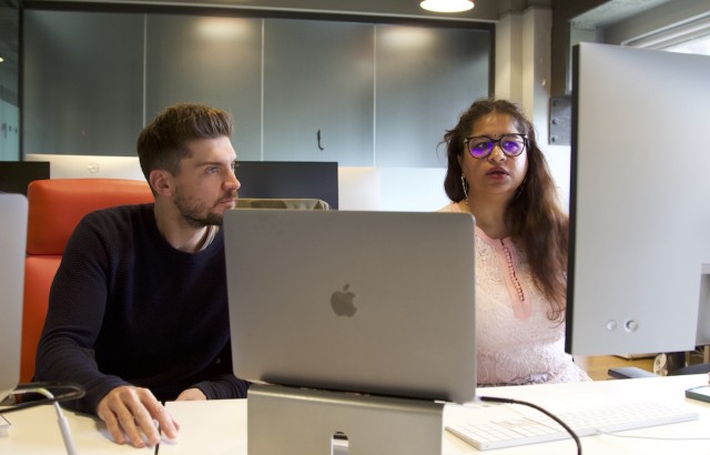 Two members of the digital optimisation team with laptops in front of them looking at a monitor at their desk