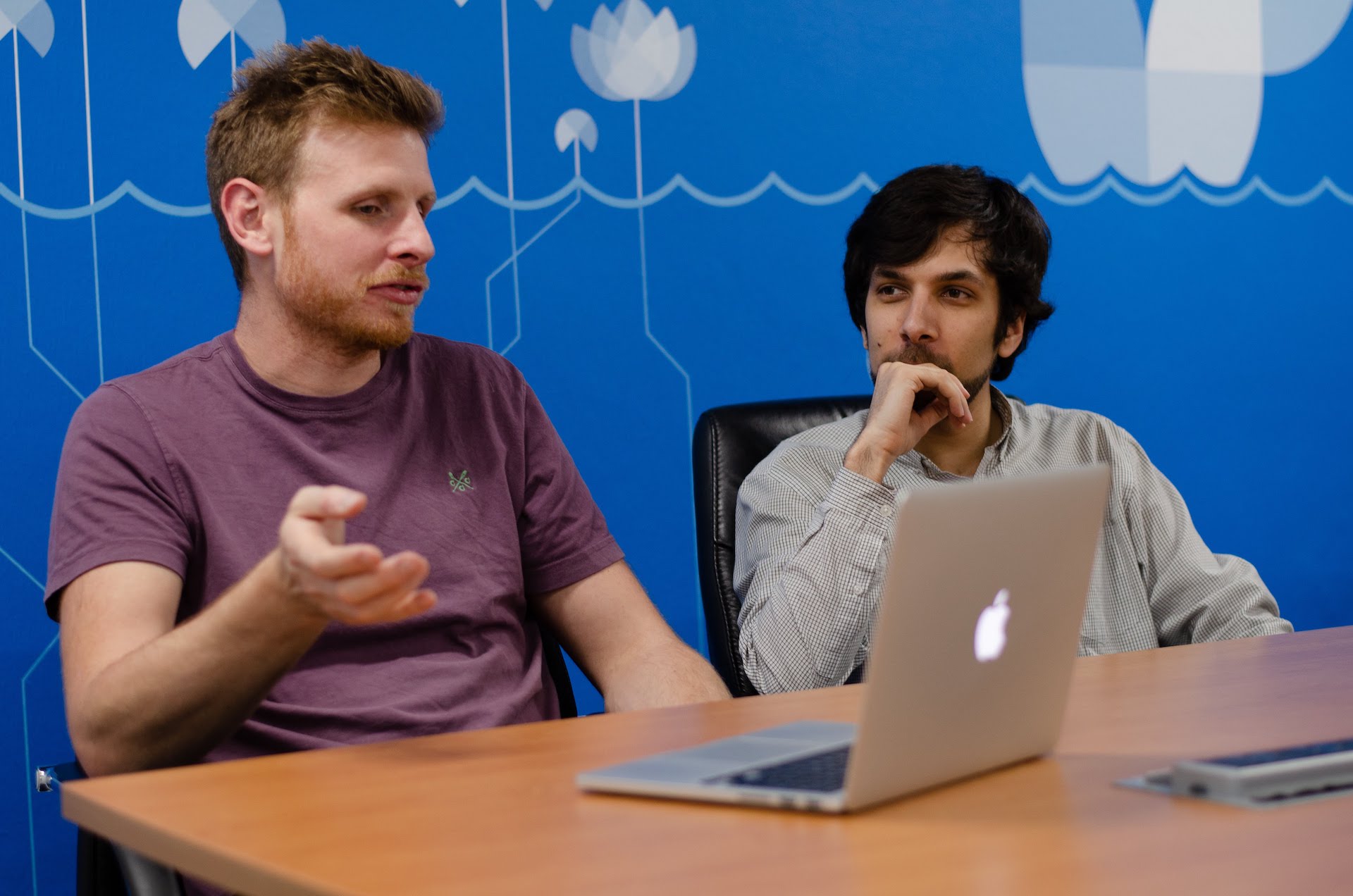 Two Cyber-Duck developers seated at a table in the office, having a discussion.